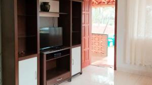 a living room with a tv in a entertainment center at Chalé Confortável e Completo com piscina in Caeté