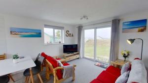 a living room with a red couch and a table at F11 Roslyn, Riviere Towans in Hayle +16 photos