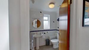 a white bathroom with a sink and a toilet at F11 Roslyn, Riviere Towans in Hayle