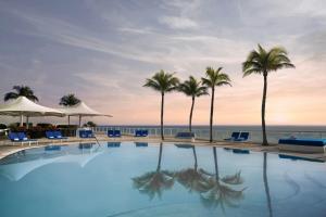 una piscina con palme e l'oceano di The Ritz-Carlton, Fort Lauderdale a Fort Lauderdale