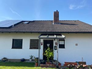 una casa blanca con un panel solar en el techo en Ferienwohnung Münnerstadt, en Münnerstadt