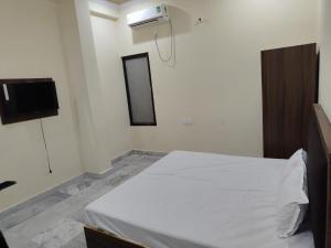 a bedroom with a white bed and a tv at Kavya Galaxy in Panki