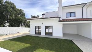 una casa bianca con un prato verde di Casa da Praia, piscina a sal, aquecida e coberta -Praia da Barra a Praia da Barra