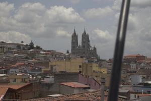a view of a city with a cathedral in the background at Hostal History in Quito