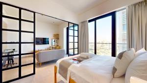 a bedroom with a large white bed and a living room at The Community Jumeirah Village in Dubai