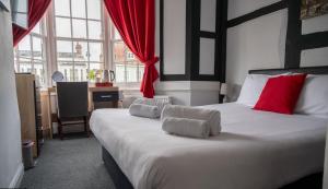 费勒姆The Bugle Hotel的卧室里有一张白色的大床，上面有红色的枕头