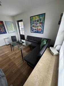 a living room with a black couch and a glass table at Fewo Zum Wohlfühlen in Hemmoor