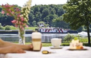 a table with a boat on a river and a table with flowers at Landgasthof Zur schönen Wienerin in Marbach an der Donau