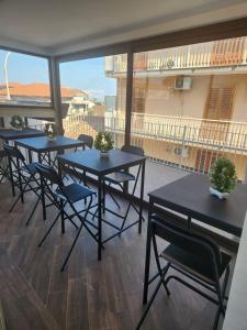 a room with tables and chairs and a balcony at Palazzo Grecale Dell'Etna in Aci SantʼAntonio