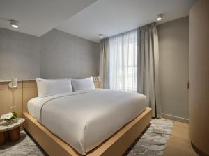 a large white bed in a room with a window at CORNER - Luxury Serviced Apartments in Montréal