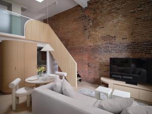 a living room with a white couch and a brick wall at CORNER - Luxury Serviced Apartments in Montréal