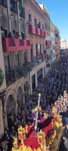 een menigte mensen die voor een gebouw met een kruis zitten bij Ispal Apartment & ParkingOptional Seville Historic Center vutse06601 in Sevilla