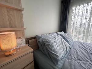 a bedroom with a bed with a lamp on a night stand at Charming condo 5min walk to MRT near DMK,Chatuchak in Bangkok +13 photos