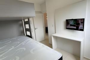 a bedroom with a bed and a tv on a wall at Apartamento em Bertioga - SP (2) in Ilha Monte Pascoal +32 photos