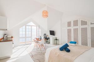 a white room with a bed and a kitchen at Casa Serena Apartments in Arco da Calheta