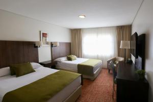 um quarto de hotel com duas camas e uma escrivaninha em Hotel Bahia Redonda em El Calafate