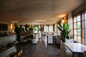 um restaurante com mesas, cadeiras brancas e janelas em Hotel Bahia Redonda em El Calafate