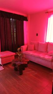 a pink living room with a couch and a table at Hospedaje in Jardín América