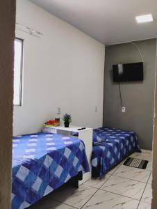 a bedroom with two beds and a tv on the wall at Apartamento Cavalcante in Belém