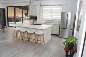 a kitchen with a white island and a refrigerator at Casa con Piscina y jacuzzi, vista al Volcán Tenorio in Martirio