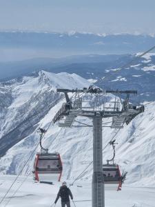a man riding a ski lift on a snow covered mountain at Chalet Gudauri in Gudauri