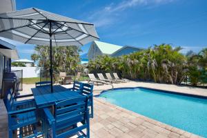 a blue table with an umbrella next to a swimming pool at Anchors Away by Sun Palace Vacations in Fort Myers Beach
