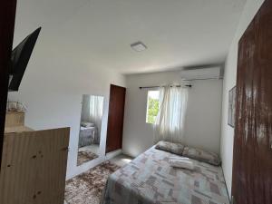 a white bedroom with a bed and a mirror at Suites Milagrense in São Miguel dos Milagres