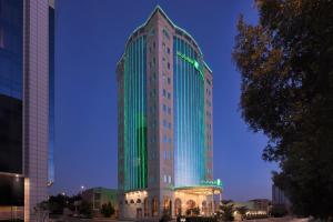 a tall building is lit up in green at Holiday Inn Riyadh AI Malaz by IHG in Riyadh