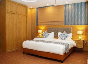 un dormitorio con una cama con sábanas y almohadas blancas en Palette Luxury Credi Hotel, en Riad