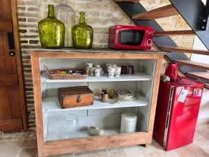 a shelf with two wine bottles and a red microwave at chambre d'hotes à la campagne in Gâprée