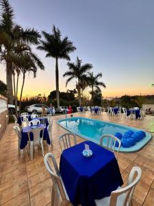 une piscine avec des tables et des chaises bleues et des palmiers dans l'établissement Casa de Campo em Juiz de Fora Granja 6 de Maio, à Chácara