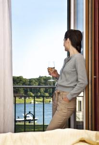 a woman holding a glass of wine looking out a window at Landgasthof Zur schönen Wienerin in Marbach an der Donau
