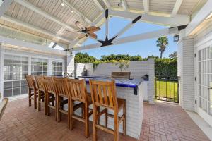 a patio with a bar with chairs and a ceiling fan at NEW Luxury Country Club Hot tub Gym Pool House Outdoor Kitchen EVENTS in Ocala