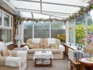 a living room with a conservatory with couches and flowers at Cosy Corner in Bessingby