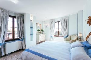 a white bedroom with a large bed and windows at Deluxe Apartments Lagoon View in Venice