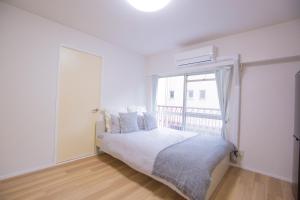 a white bedroom with a bed and a window at 新宿駅 西武新宿駅近 歌舞伎町の快適ゲストハウス LoE3 in Tokyo