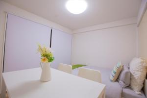 a white dining room with a vase of flowers on a table at 新宿駅 西武新宿駅近 歌舞伎町の快適ゲストハウス LoE3 in Tokyo +10 photos