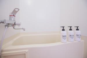 three bottles ofodorizers sit on a counter next to a sink at 新宿駅 西武新宿駅近 歌舞伎町の快適ゲストハウス LoE3 in Tokyo