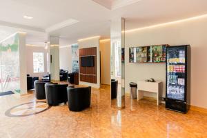 a lobby with black chairs and a tv in a building at Hotel Oly Plaza in Piracicaba