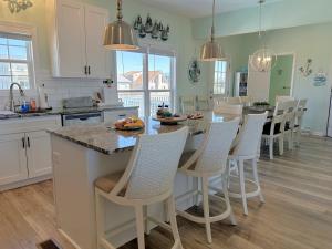 a kitchen with a large island with white cabinets and chairs at Key Rest in Oak Island