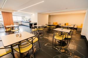 an empty dining room with tables and yellow chairs at Hotel Oly Plaza in Piracicaba