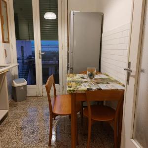 a kitchen with a table with chairs and a refrigerator at Camera "La Margherita" in Pistoia