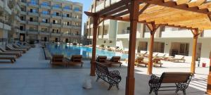 una piscina con bancos y mesas y un edificio en Elhambra First Avenue, en Hurghada