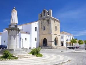 a church with a tower in front of a building at Brigida's Flat in Faro