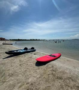 two kayaks sitting on a beach next to the water at Golden Lake Residence Apart Hotel in Arraial do Cabo