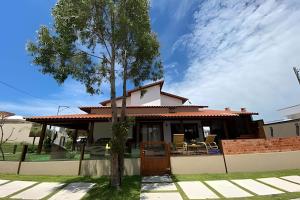 une maison avec un arbre devant dans l'établissement Casa em São Pedro da Aldeia - RJ, à São Pedro da Aldeia