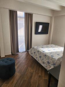 a bedroom with a bed and a table and a television at Palazzo Grecale Dell'Etna in Aci SantʼAntonio