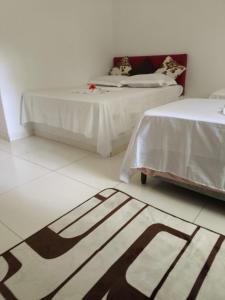 a room with two beds and a rug on the floor at Bella Morena 1 Ilha de Boipeba in Ilha de Boipeba