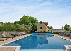a large swimming pool with chairs and a barn at Willow Warbler - HM112 - Lower Mill Estate Penthouse Apartment with Spa Access in Somerford Keynes