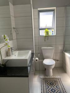 a bathroom with a sink and a toilet and a window at WeThusi-CBD in Mbabane
